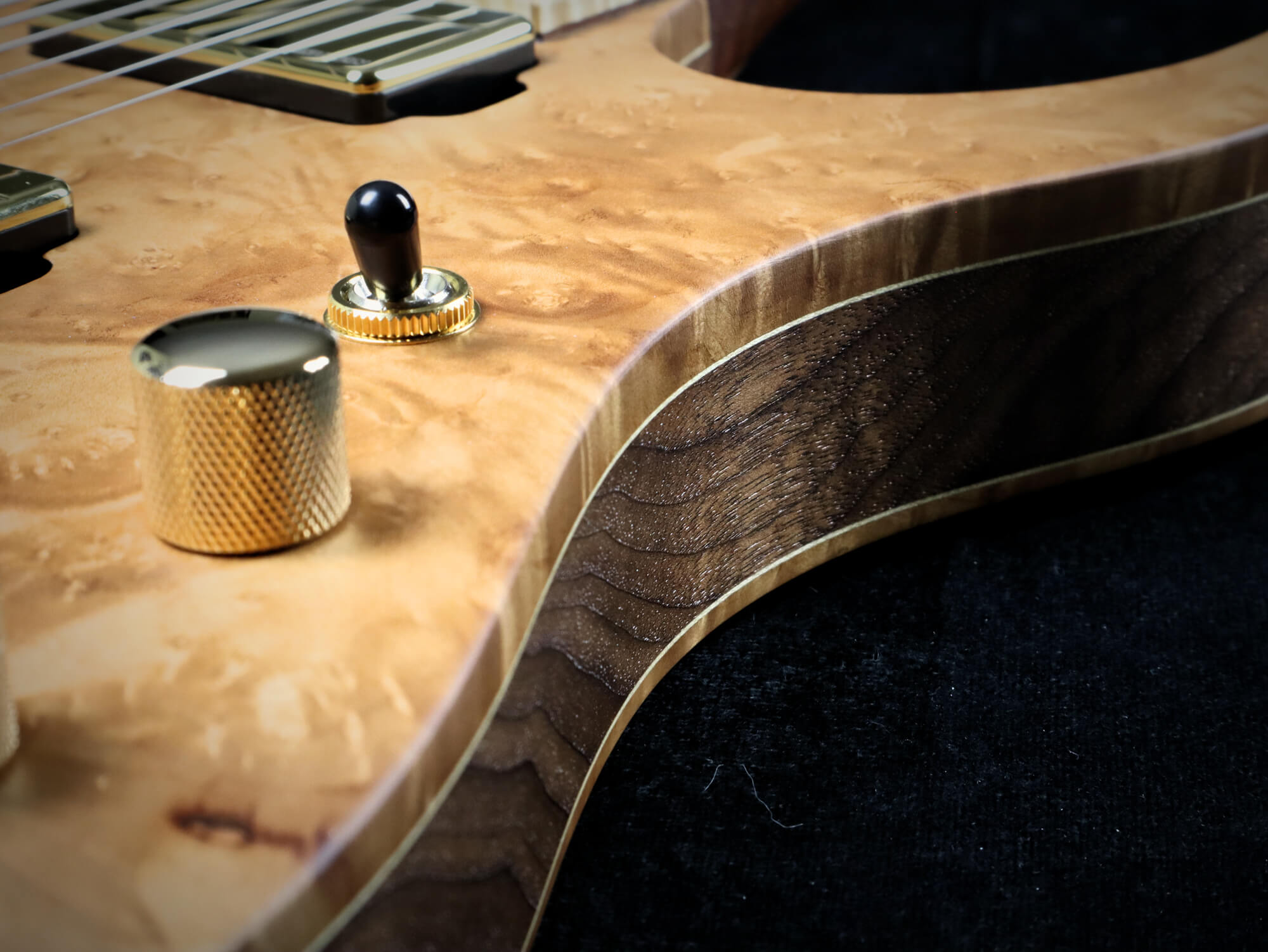 A side view of of a Madrone burl electric guitar finished with Rubio Monocoat products.