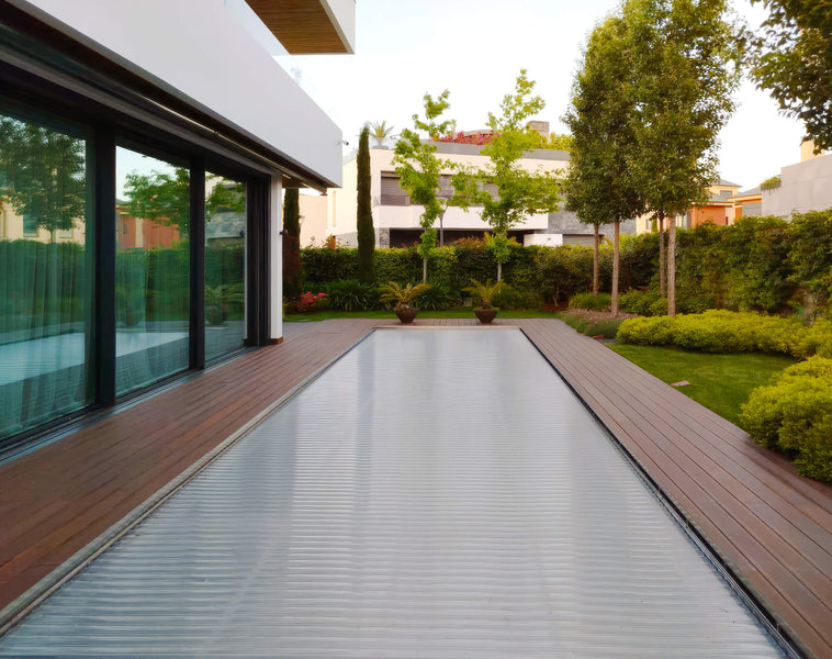 A pool deck made from bamboo wood surrounding a pool in a residential home. 