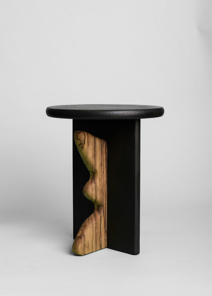 A modern side table with an organically shaped piece of black limba attached. 