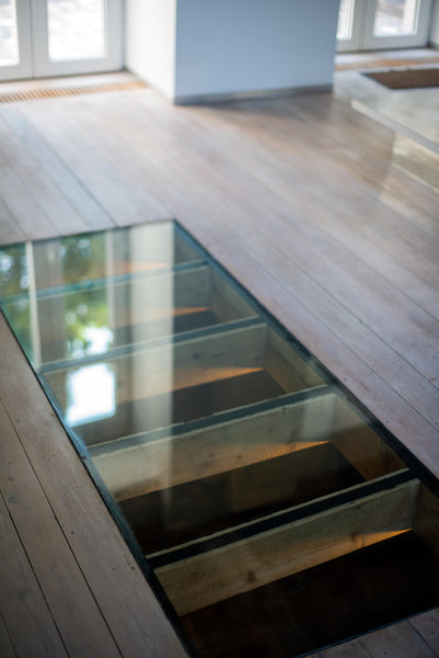 Wood flooring finished using Rubio Monocoat Oil Plus 2C with an integrated glass piece that looks into the floor below. 