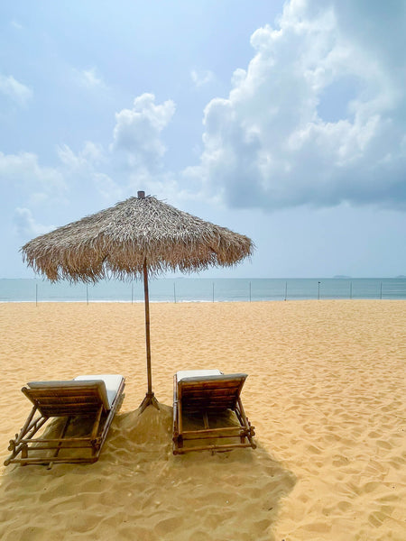 Two lounge chairs and an umbrella on a beach. The furniture was made from recycled materials and finished using DuroGrit, a very durable exterior wood finish. 