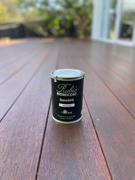 A can of DuroGrit, an extremely durable exterior wood finish sitting on top of a wooden deck finished with the product. 