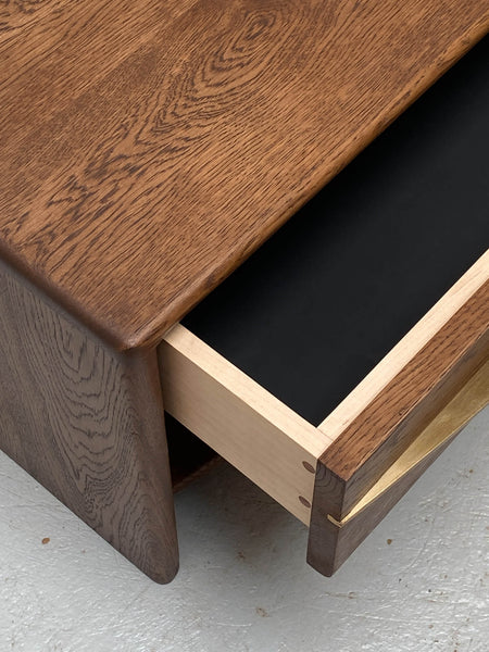 A European oak nightstand with a drawer slightly ajar finished with a durable hardwax oil wood stain and finish.