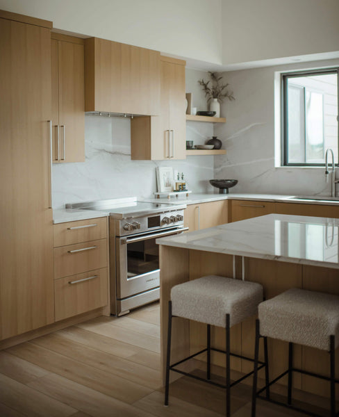 A beautiful kitchen with white oak cabinetry, a large island, and white stone countertops.