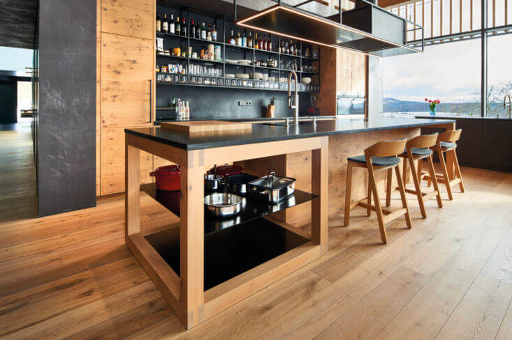 Wooden kitchen with dark counter tops and hardwood flooring.