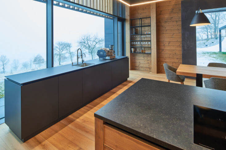 European oak wood flooring in kitchen with large windows looking over forest.